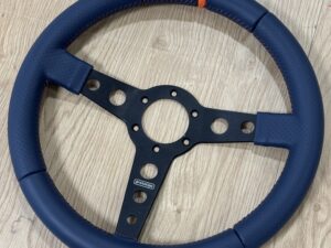 Volant 3 branches sportif en cuir bi-matière surpiqûre orange, et rappel à midi orange.